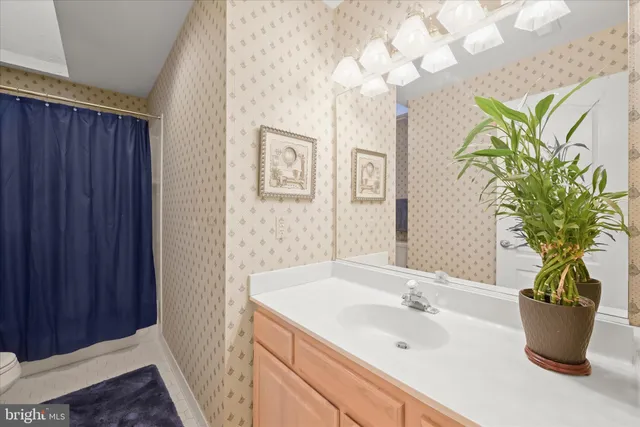 a bathroom with a granite countertop sink a toilet a large mirror and shower