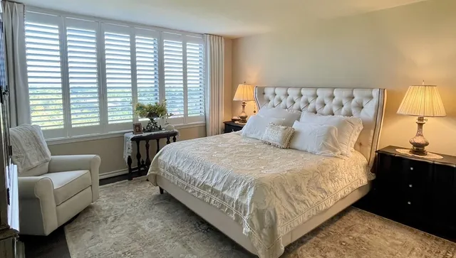 a bedroom with a bed and large windows