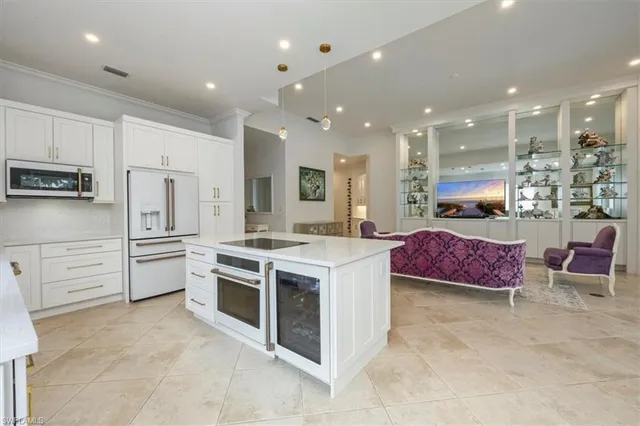 a large kitchen with stainless steel appliances granite countertop a stove a sink a refrigerator and white cabinets