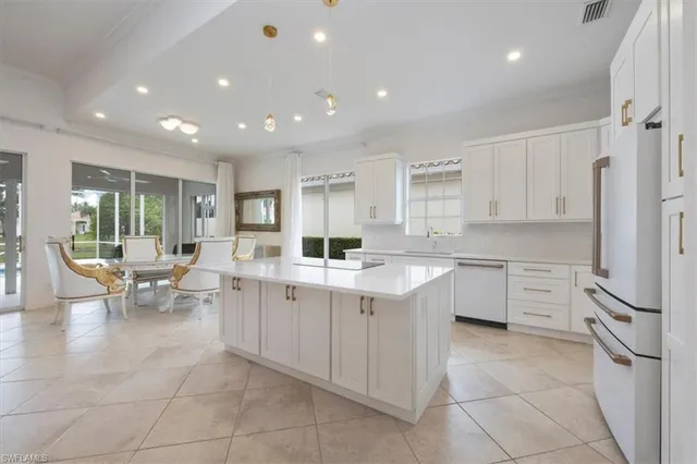 a large kitchen with a large counter top space a sink stainless steel appliances and cabinets