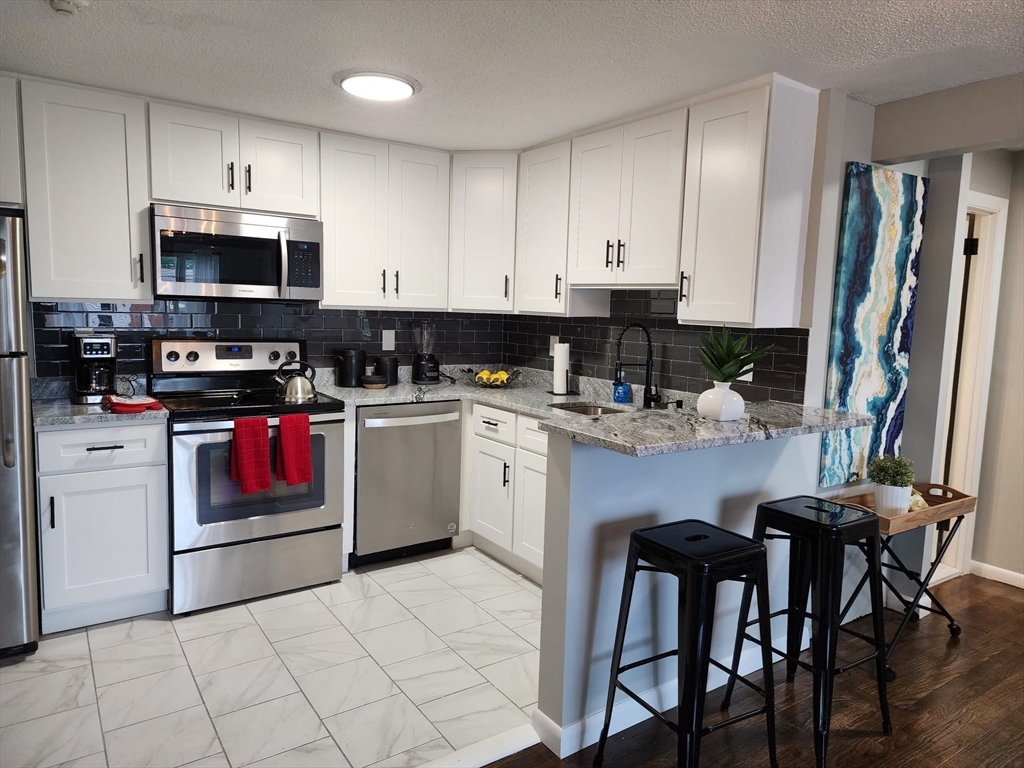 99 Cluff Crossing Road, Unit B12 Salem, NH 03079 - Photo 5 of 12 a kitchen with a stove a sink and white cabinets