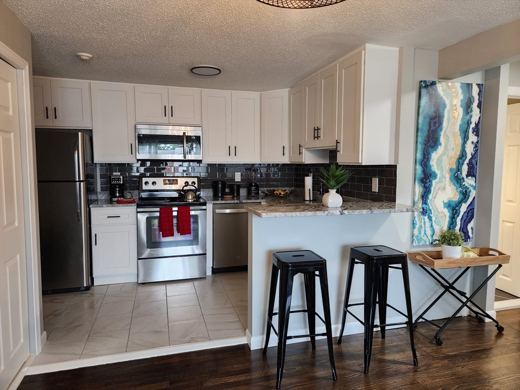 99 Cluff Crossing Road, Unit B12 Salem, NH 03079 - Photo 7 of 12 a kitchen with stainless steel appliances granite countertop a stove top oven a refrigerator and cabinets