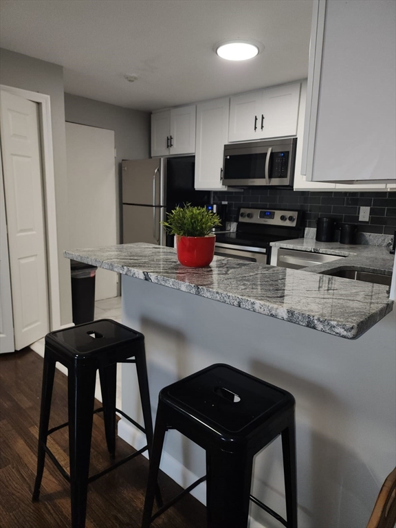 99 Cluff Crossing Road, Unit B12 Salem, NH 03079 - Photo 10 of 12 a kitchen with stainless steel appliances granite countertop a table chairs microwave and sink