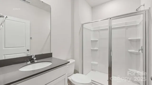 a bathroom with a granite countertop sink toilet a mirror a shower and a vanity