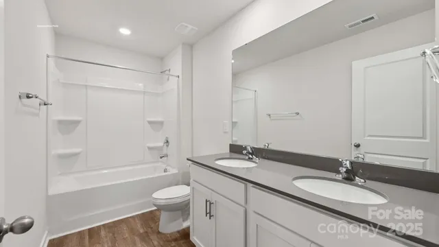 a bathroom with a granite countertop sink toilet a large mirror a bathtub and shower