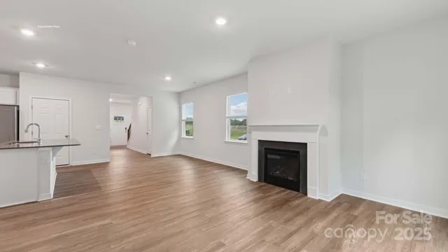 a view of an empty room with wooden floor and a fireplace