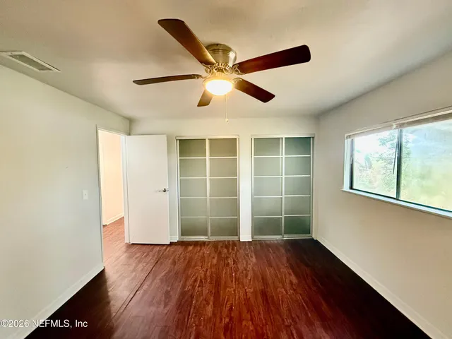 a view of empty room with wooden floor and fan
