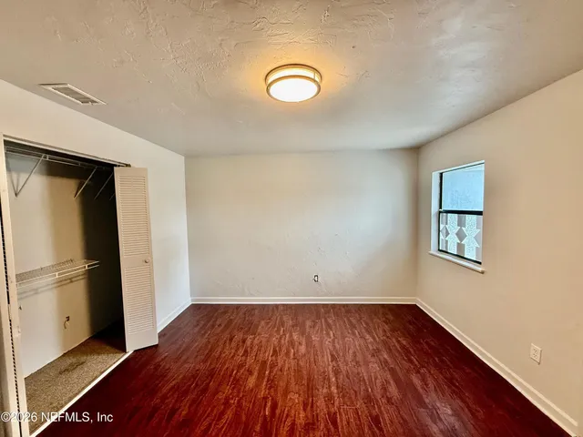 a view of a room with wooden floor and a refrigerator