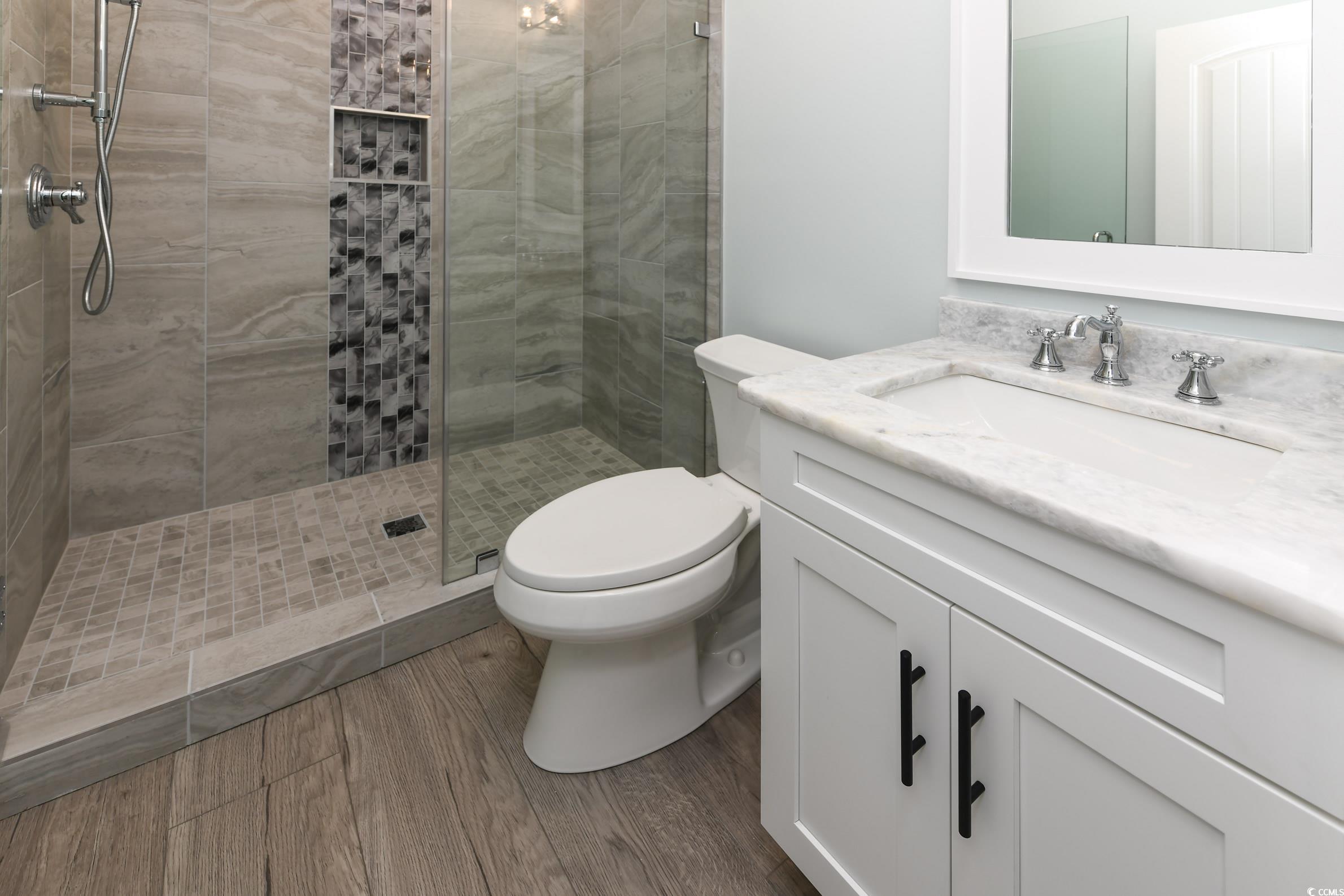 2349 South Waccamaw Drive Murrells Inlet, SC 29576 - Photo 31 of 39 Bathroom with toilet, vanity, a tile shower, and wood finished floors