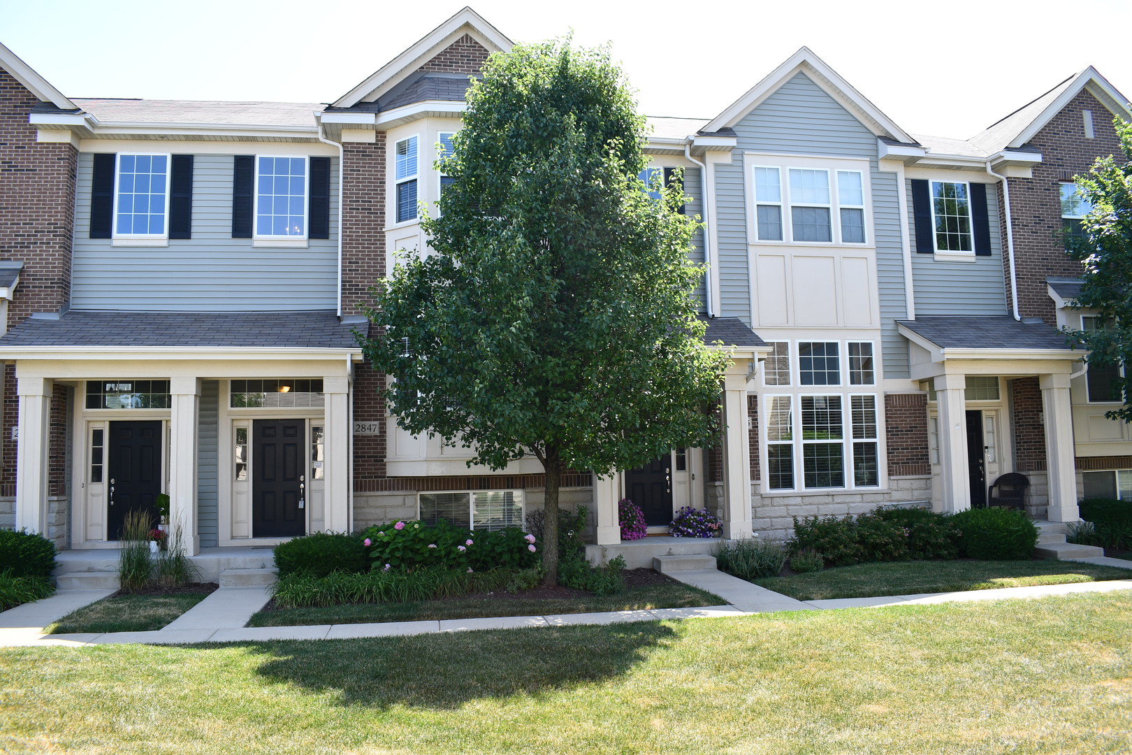 a front view of a house with garden and trees