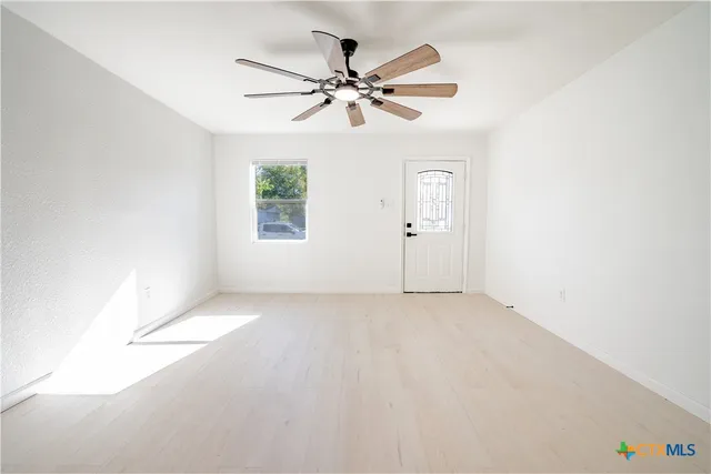 an empty room with windows and fan