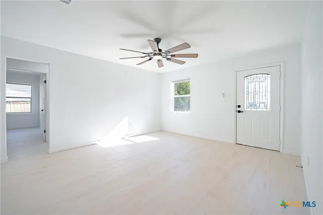 an empty room with windows and chandelier fan