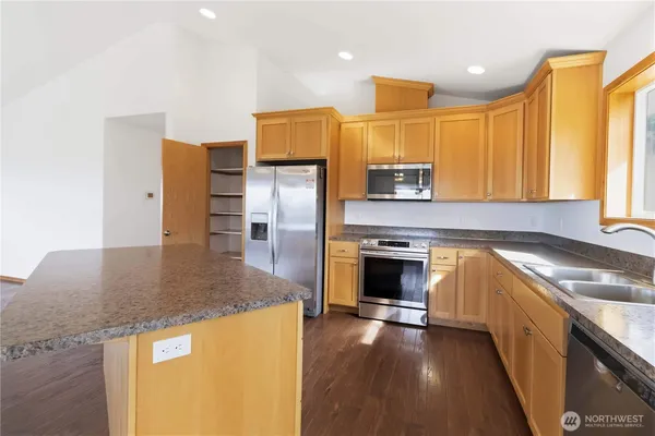 a kitchen with stainless steel appliances granite countertop a sink a stove and a refrigerator