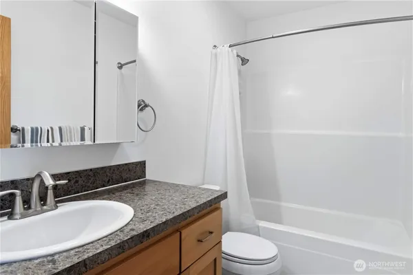 a bathroom with a granite countertop sink toilet and shower