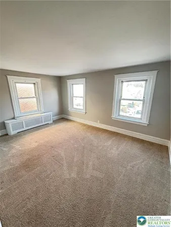 en empty room with windows and chandelier fan