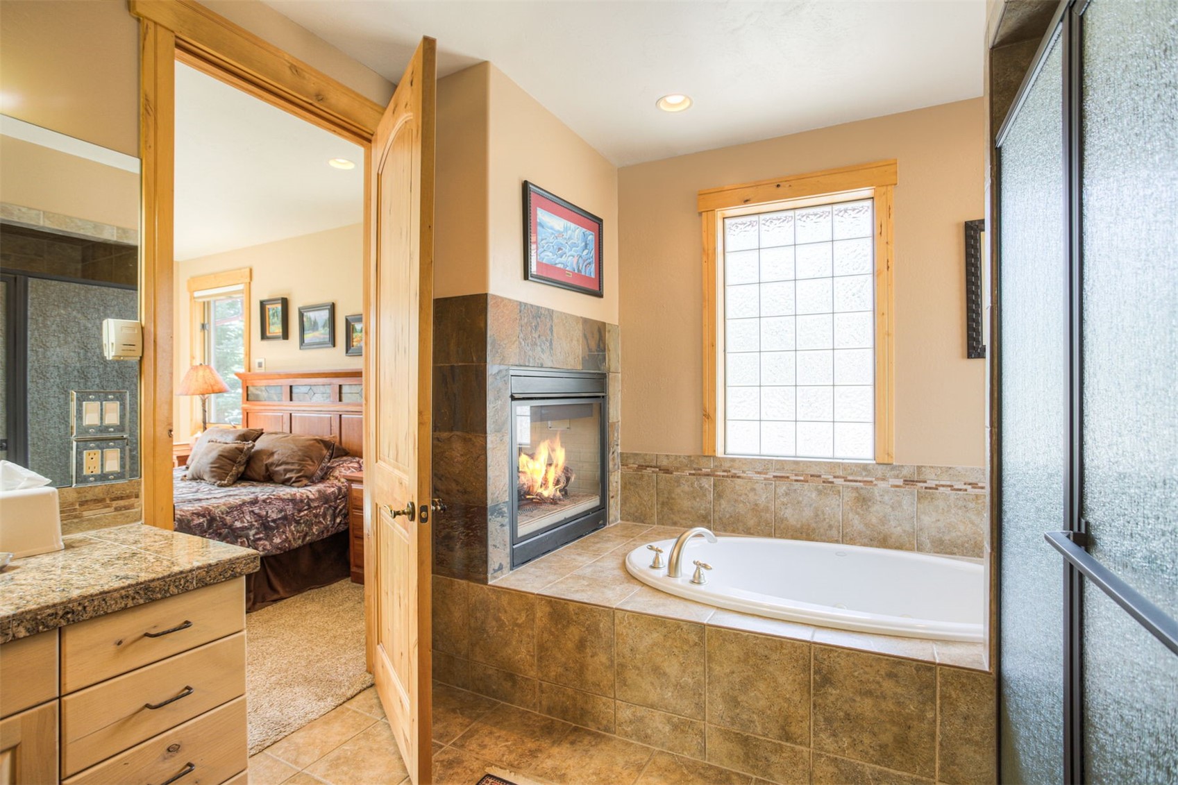 727 Willowbrook Road Silverthorne, CO 80498 - Photo 27 of 47 Ensuite bathroom with a stall shower, vanity, a tiled fireplace, a garden tub, and light tile patterned flooring