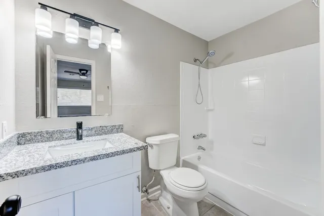a bathroom with a granite countertop sink toilet and shower