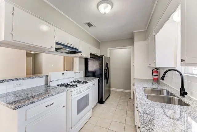 a kitchen with stainless steel appliances granite countertop a sink stove and refrigerator