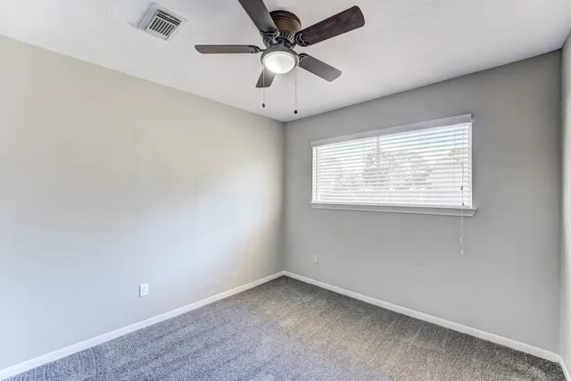 an empty room with a window and a ceiling fan