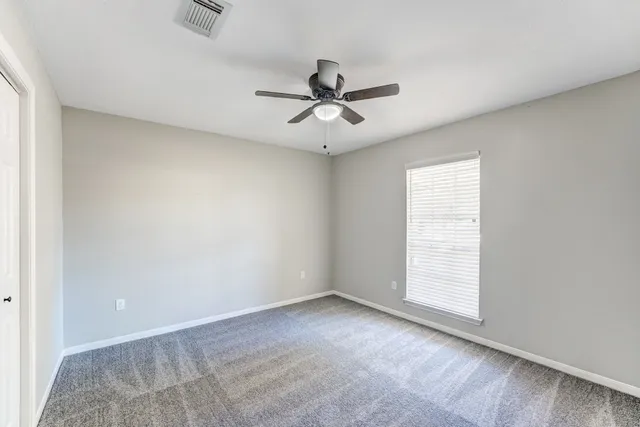 an empty room with windows and fan