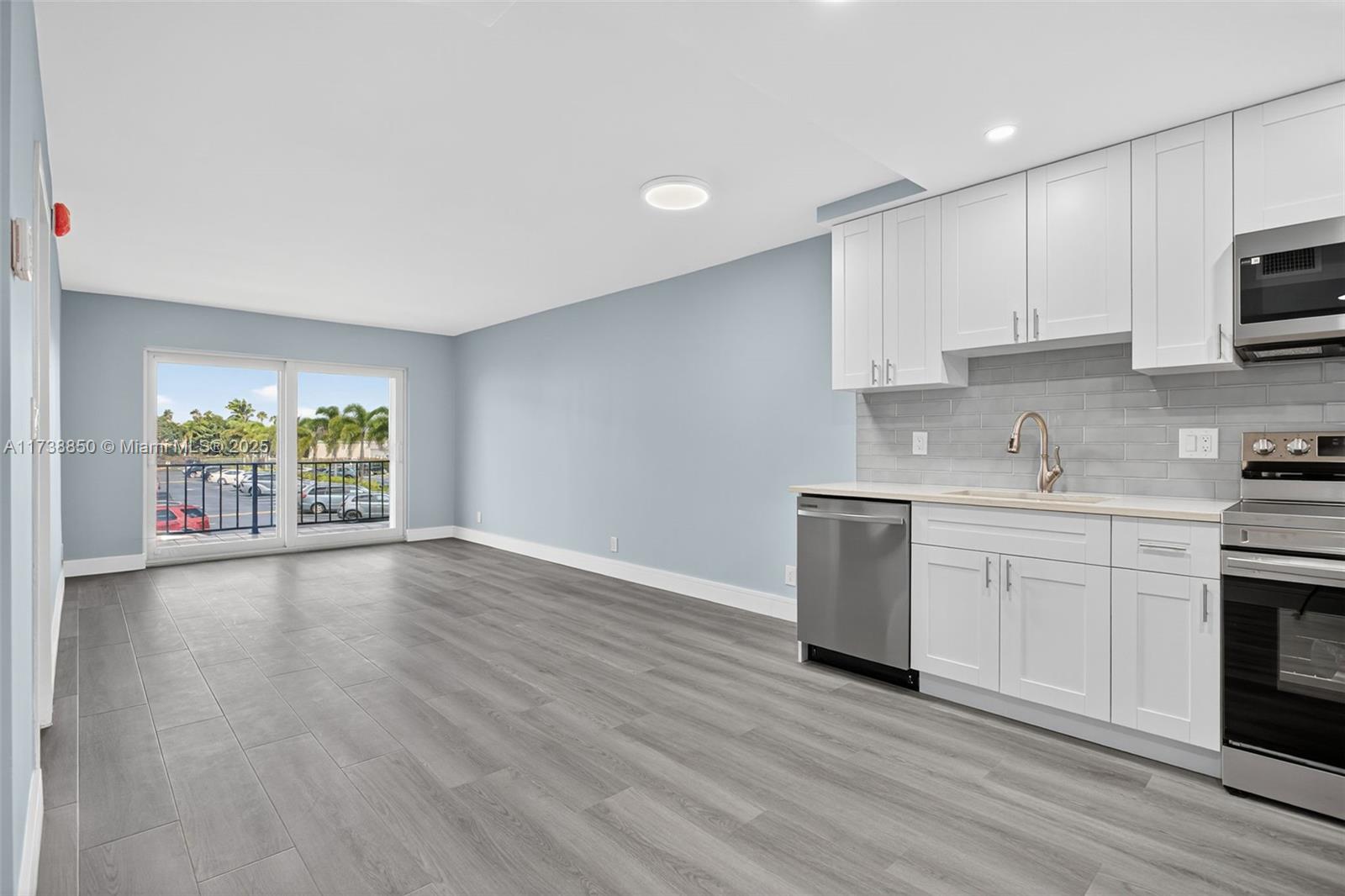 3004 Northeast 5th Terrace, Unit 214C Wilton Manors, FL 33334 - Photo 24 of 99 a kitchen with granite countertop a stove a sink and a microwave