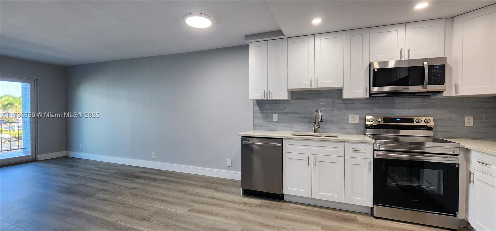 3004 Northeast 5th Terrace, Unit 214C Wilton Manors, FL 33334 - Photo 25 of 99 a kitchen with stainless steel appliances granite countertop a stove a sink and a microwave