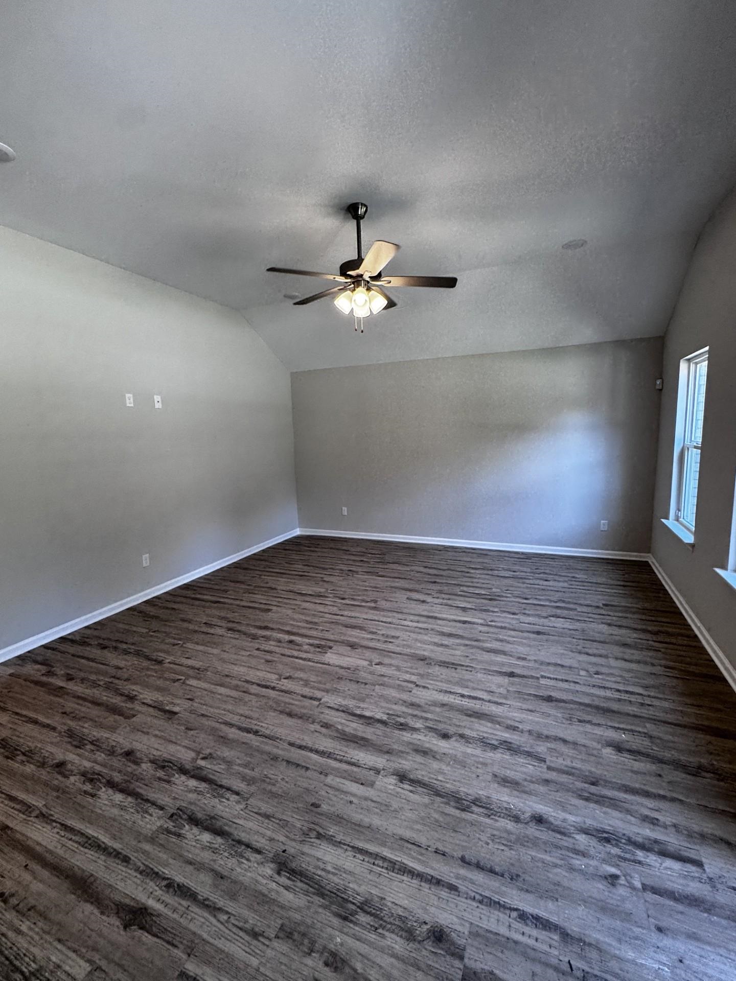 5263 Zodiac Road Memphis, TN 38118 - Photo 4 of 9 Empty room featuring lofted ceiling, dark wood finished floors, a textured ceiling, and a ceiling fan
