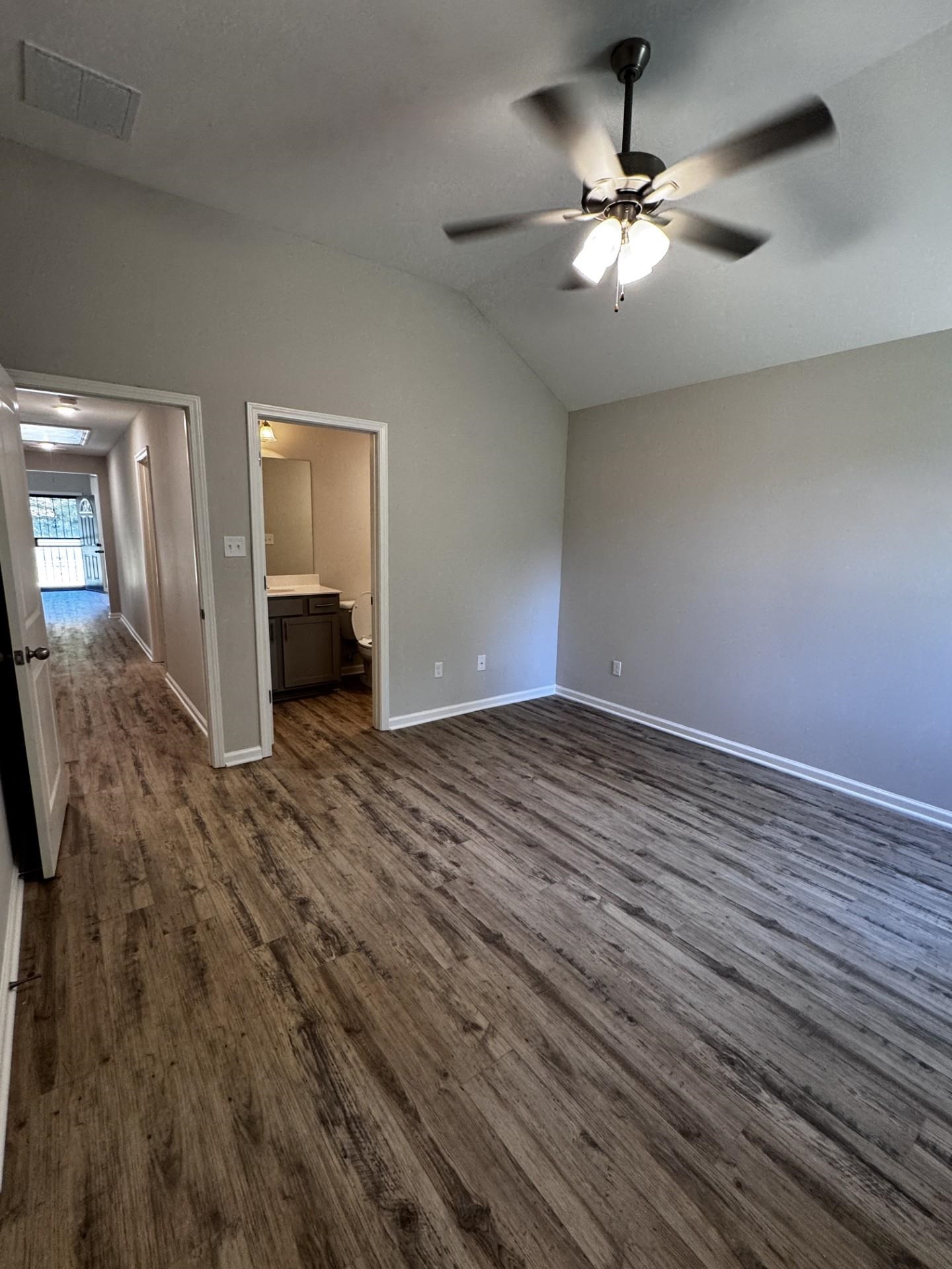 5263 Zodiac Road Memphis, TN 38118 - Photo 7 of 9 Unfurnished bedroom with connected bathroom, dark wood-type flooring, vaulted ceiling, and ceiling fan