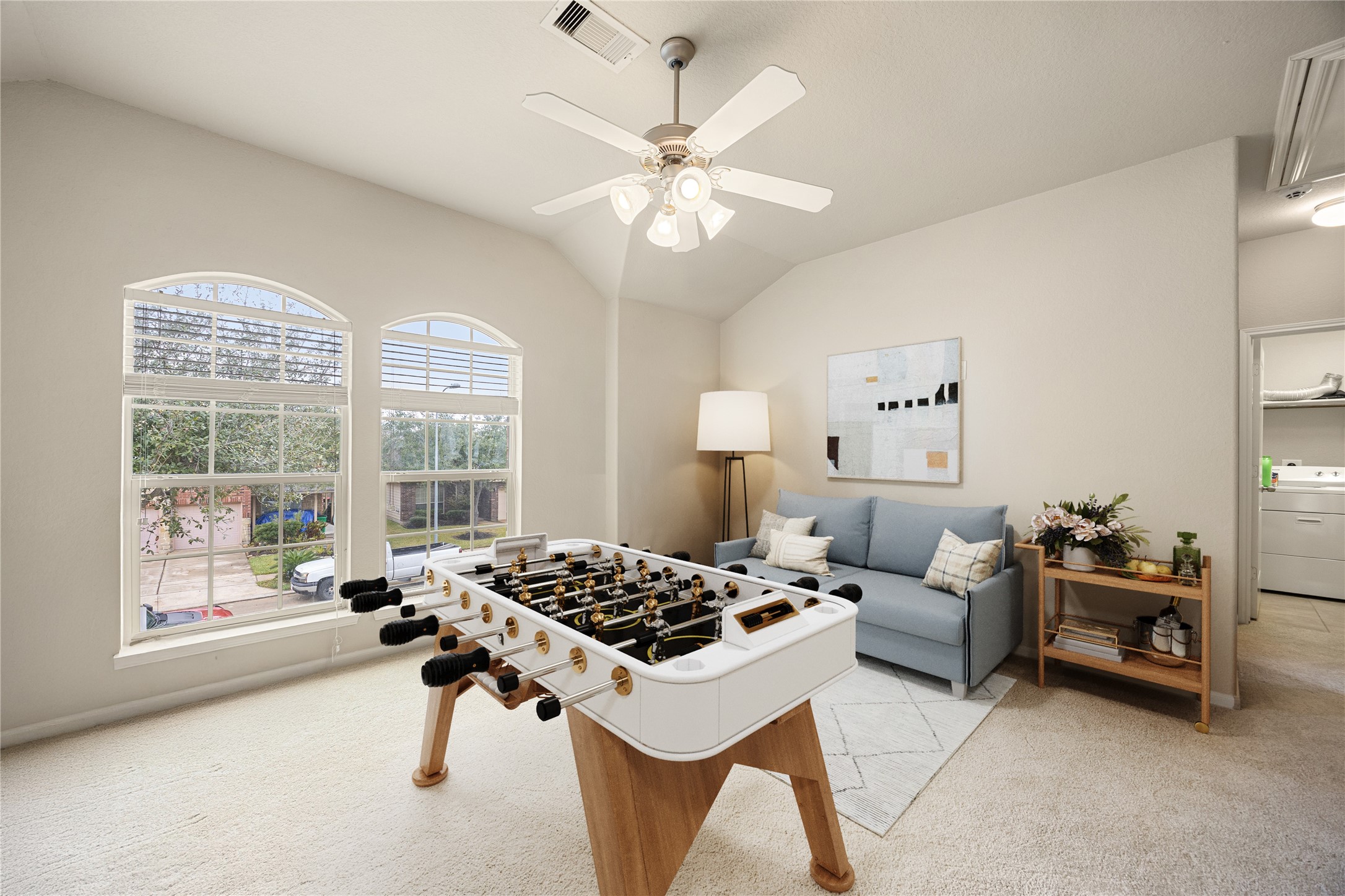 3526 Canvasback Lane Houston, TX 77047 - Photo 12 of 22 Upstairs, enjoy a spacious and versatile game room, featuring plush carpeting, a vaulted ceiling, ceiling fan with light fixture, and large arched windows that fill the space with natural light—perfect for relaxing, gaming, or creating a comfortable secondary living area. *Virtually Staged