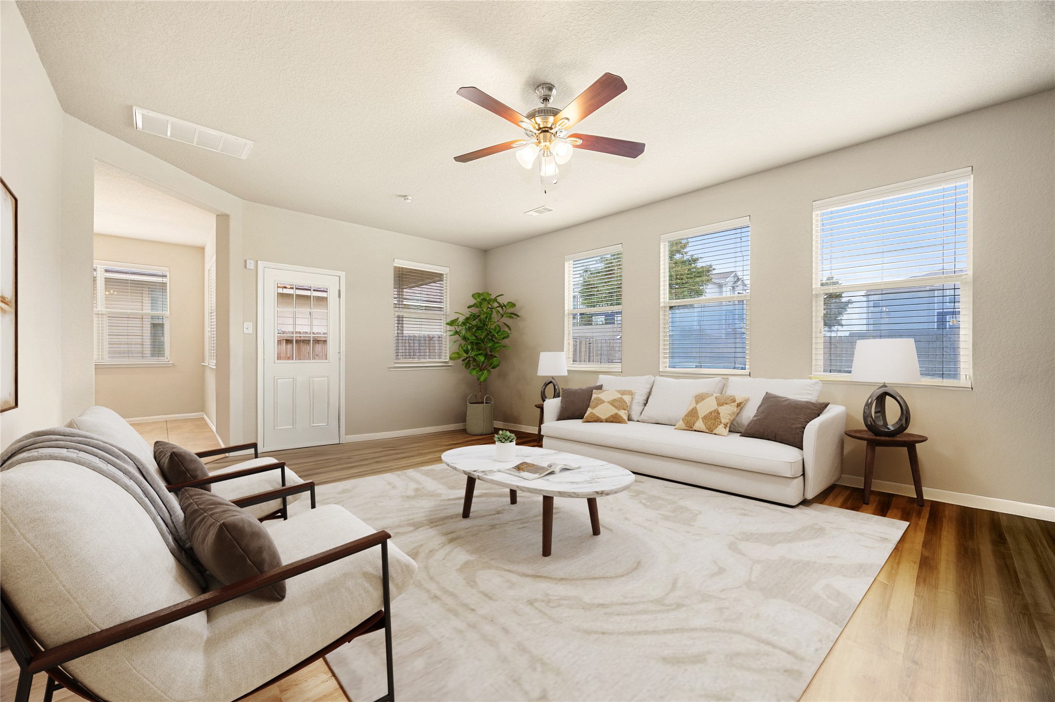 3526 Canvasback Lane Houston, TX 77047 - Photo 6 of 22 Gather the family and guests together in this inviting living space, featuring high ceilings, a dark-stained ceiling fan with light fixture, wood-look flooring, neutral paint tones, and multiple windows that fill the room with natural light, creating a bright and comfortable setting for everyday living. *Virtually Staged