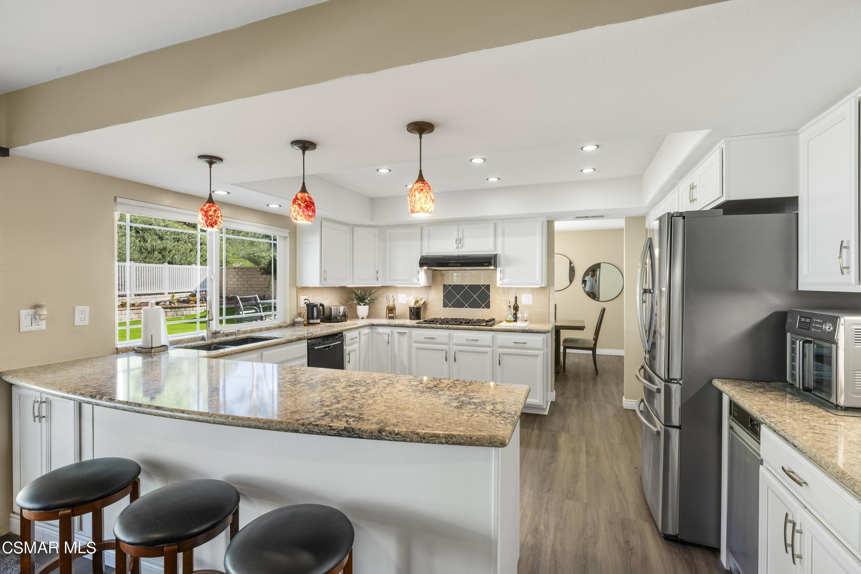 2992 Chippewa Avenue Simi Valley, CA 93063 - Photo 21 of 35 a kitchen with stainless steel appliances granite countertop a refrigerator a sink a stove and a dining table with wooden floor