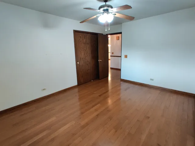 an empty room with wooden floor and fan