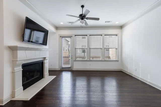 a view of an empty room with wooden floor and a fireplace