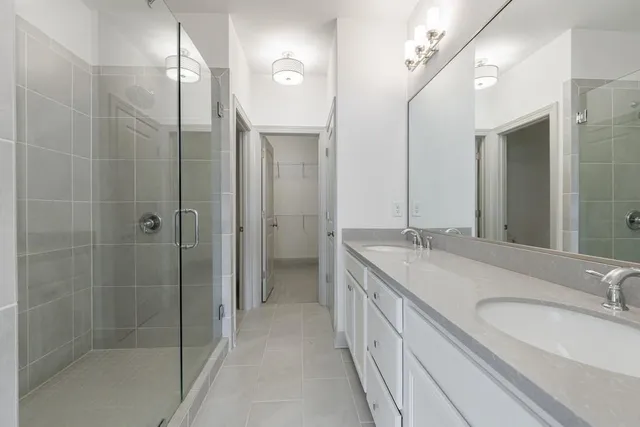 a bathroom with a granite countertop sink a large mirror and a shower