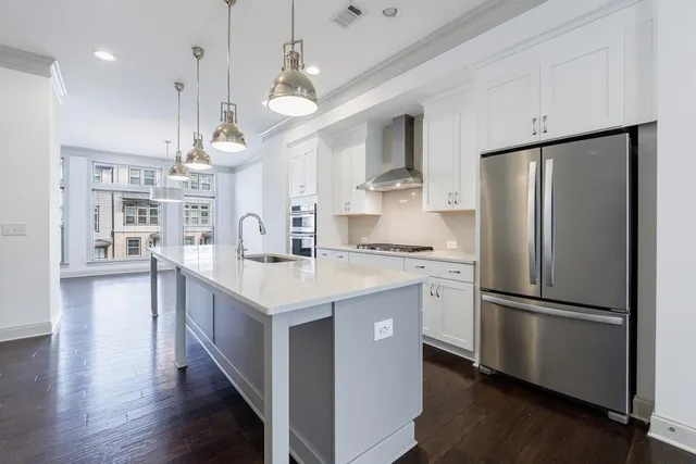 a kitchen with stainless steel appliances granite countertop a refrigerator a sink dishwasher a oven and a refrigerator with wooden floor