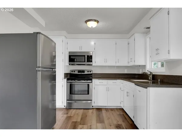a kitchen with granite countertop a refrigerator and a stove top oven