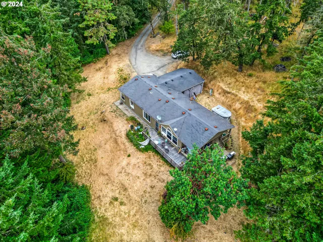 an aerial view of a house with a yard and trees all around