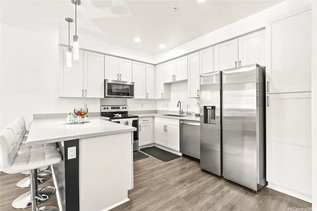 a kitchen with a refrigerator a microwave oven a sink and a dining table with wooden floor