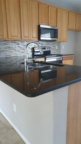 a kitchen with granite countertop a sink a stove and a microwave