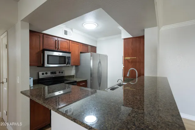 a kitchen with stainless steel appliances granite countertop a refrigerator a stove top oven a sink and dishwasher