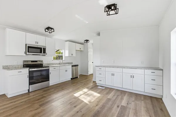 a kitchen with granite countertop white cabinets and white appliances