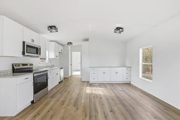 a large kitchen with cabinets wooden floor and stainless steel appliances