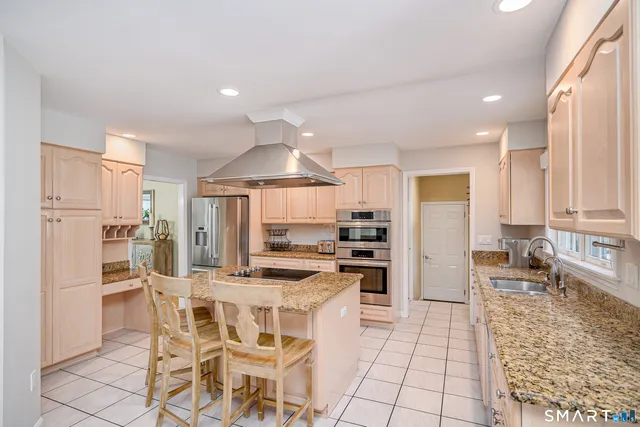 a kitchen with stainless steel appliances kitchen island granite countertop a refrigerator and cabinets