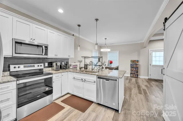 a kitchen with stainless steel appliances granite countertop a stove top oven a sink dishwasher and a refrigerator with wooden floor