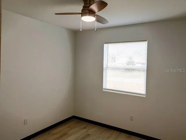 an empty room with a window and wooden floor