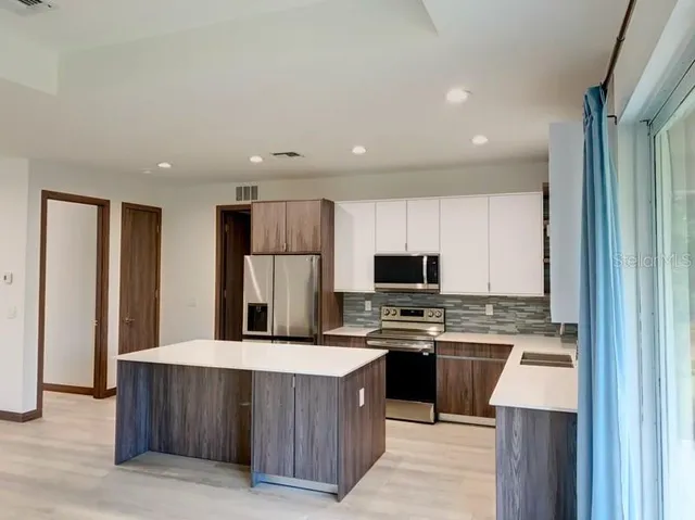 a kitchen with stainless steel appliances granite countertop a stove top oven a sink a refrigerator and a microwave