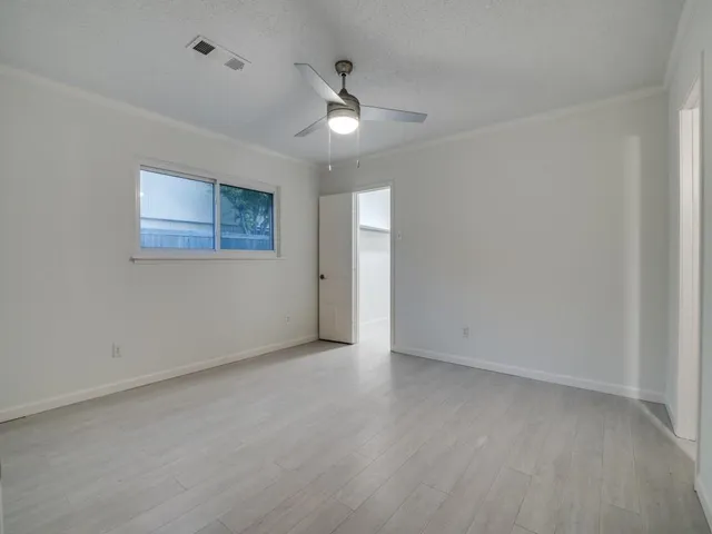 an empty room with a ceiling fan and a window