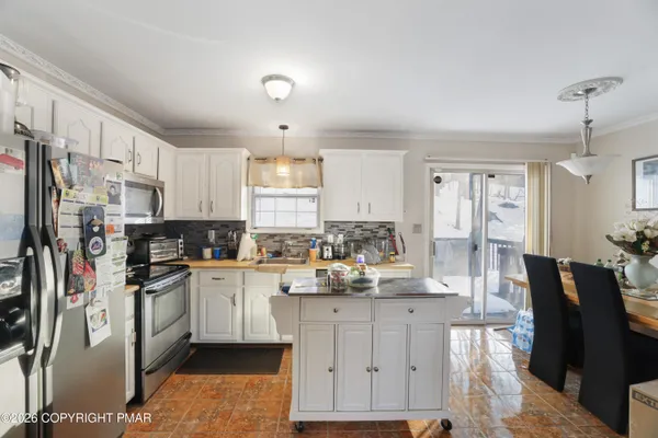 a kitchen with stainless steel appliances granite countertop a refrigerator a stove a sink dishwasher and white cabinets with wooden floor