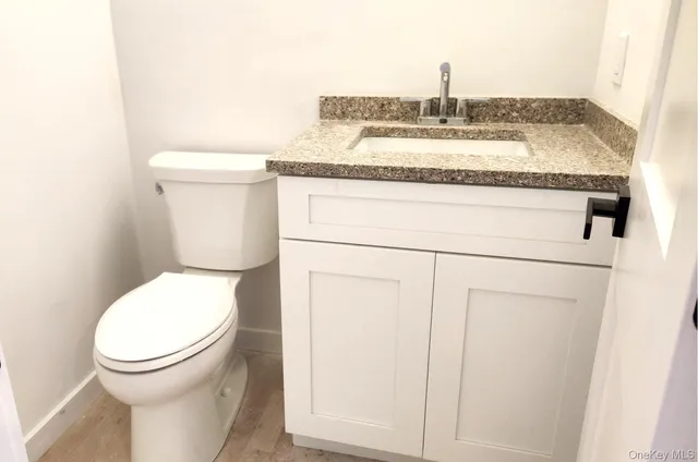 a bathroom with a granite countertop toilet and a sink