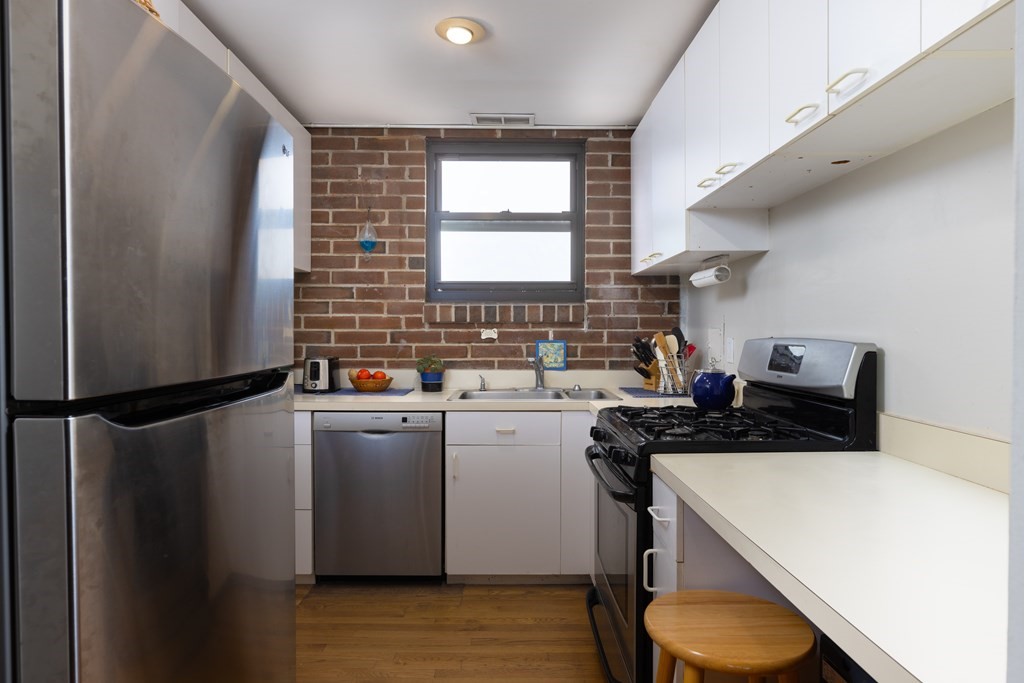 1856 Beacon Street, Unit PHA Brookline, MA 02445 - Photo 5 of 12 a kitchen with a refrigerator a sink and wooden cabinets